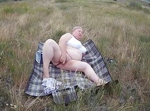 fat woman masturbates with a toy in the field