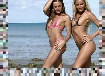 Two hot babes posing on the beach in tiny bikinis