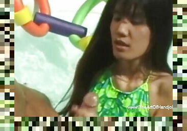 Asian MILF gives an interracial handjob by the pool